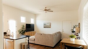 Un espacio habitable compacto con kitchenette, sofá, mesa de comedor y ventilador de techo.