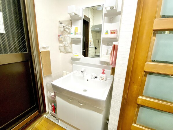 Un baño con lavamanos blanco, espejo y armarios de almacenamiento.