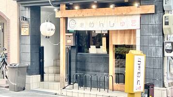 A restaurant with a wooden exterior, a sign with Japanese characters, and outdoor seating with metal chairs.