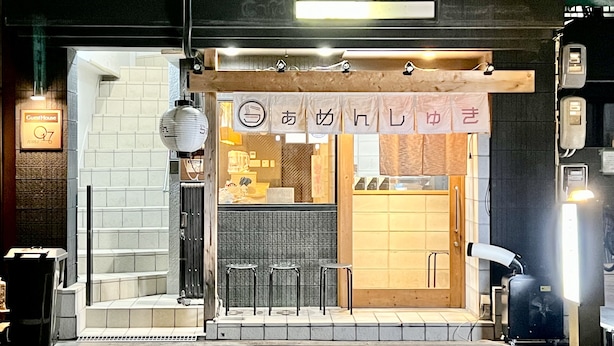 A restaurant with a wooden interior, a signboard, and three stools outside. - GuestHouse Reina osaka (Osaka)