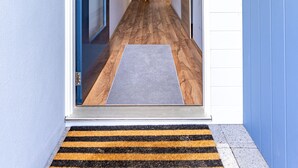 A hallway with a wooden floor, a blue door, and a mat at the entrance. - Spacious 4x3 home, just minutes away from the Margaret River main street. (Margaret River)