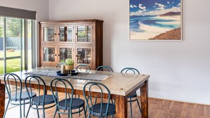 A dining area with a wooden table, six chairs, and a cabinet with glass doors. - Spacious 4x3 home, just minutes away from the Margaret River main street. (Margaret River)