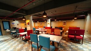 A restaurant with a checkered floor, multiple tables and chairs, and hanging pendant lights. - Mevid hotels (Hyderabad)