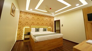 A modern hotel room with a wooden bed, a ceiling fan, and geometric patterned wallpaper. - Mevid hotels (Hyderabad)
