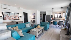 A modern living room with a teal sofa set, a coffee table, and a dining area with chairs. - Spacious villa with pool and panoramic views (Aigne)