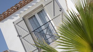 A white building with a window featuring shutters and a metal railing. - Spacious villa with pool and panoramic views (Aigne)