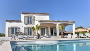 A two-story house with a swimming pool, outdoor seating, and a covered patio area. - Spacious villa with pool and panoramic views (Aigne)