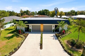 A modern building with a garage entrance, surrounded by well-maintained landscaping and palm trees.