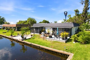 Een pand met een overdekte patio, een zwembad en een aangelegde tuin.