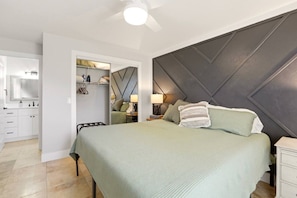 Un dormitorio con cama, mesitas de noche, un armario y un espejo.