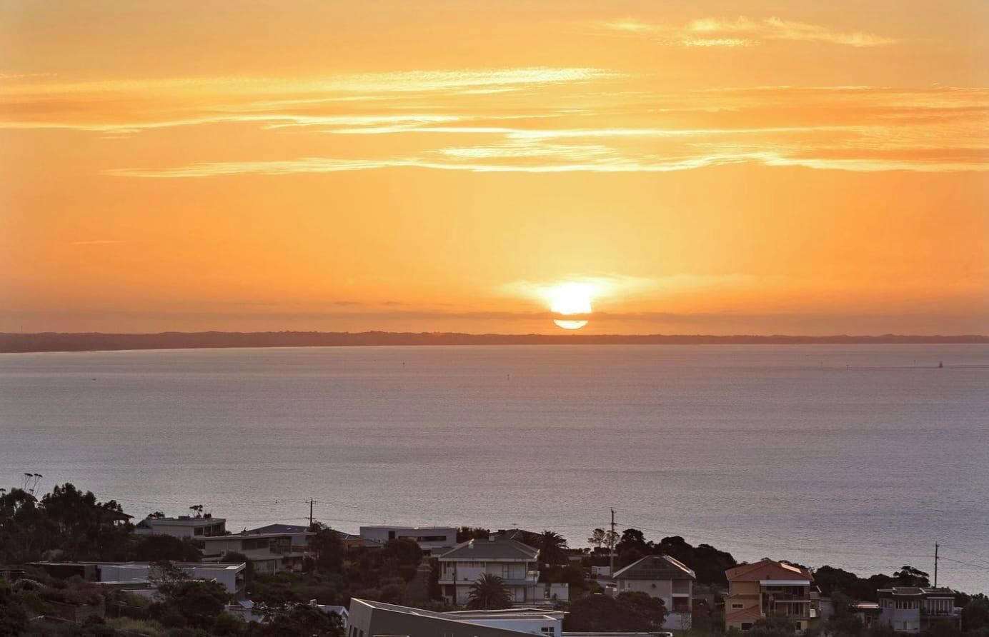 Un coucher de soleil sur la côte, avec vue sur la mer et les immeubles résidentiels.