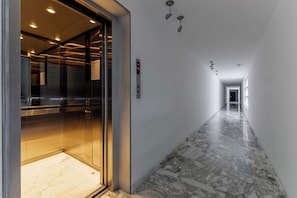 A hallway with a marble floor, an elevator, and a digital display. - Stunning Polanco 1BR Balcony & CDMX Views (Ciudad de México)