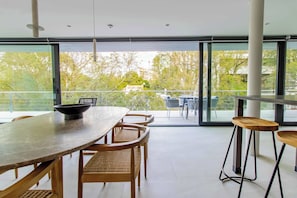 A modern dining area with a large table, wicker chairs, and a view through large glass doors to an outdoor balcony. - Stunning Polanco 1BR Balcony & CDMX Views (Ciudad de México)