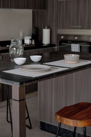 A kitchen with a marble countertop, a wooden stool, and a white pitcher.