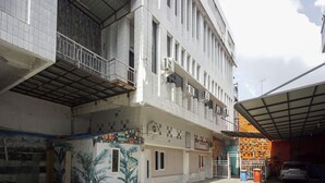 Ein mehrstöckiges Gebäude mit Kachelfassade, einem Balkon im zweiten Stock und einem überdachten Parkbereich.