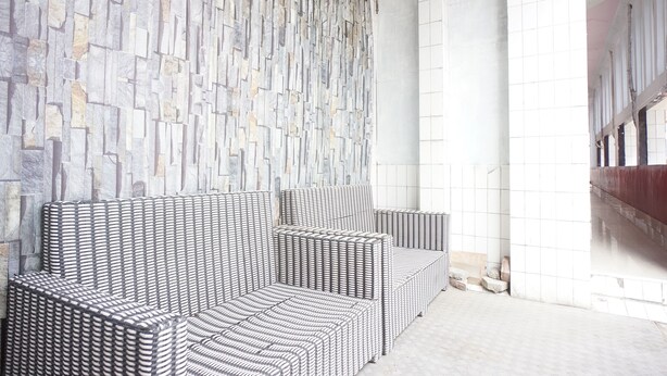 Ein Sitzbereich mit einem gemusterten Sofa und einer Wand aus Stein.