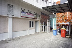 A building with a tiled exterior, a gated entrance, and two trash bins. - OYO 93003 B32 Homestay (Medan)