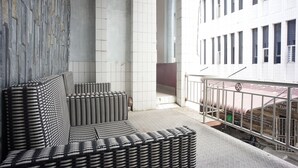 Ein modernes Interieur mit einer Steinwand, einer Sitzecke mit schwarz-weißen Kissen und Blick auf ein Gebäude mit mehreren Fenstern.