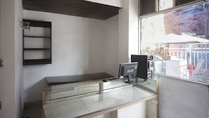 Ein Zimmer mit einem Glastisch, einem Computer und einem Fenster mit Blick auf die Umgebung.