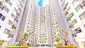 Un edificio residencial alto con varios balcones, un patio central con piscina y zonas verdes circundantes.