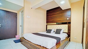 Un dormitorio con cabecera de madera, una cama grande, un cesto de ropa rosa y una puerta.