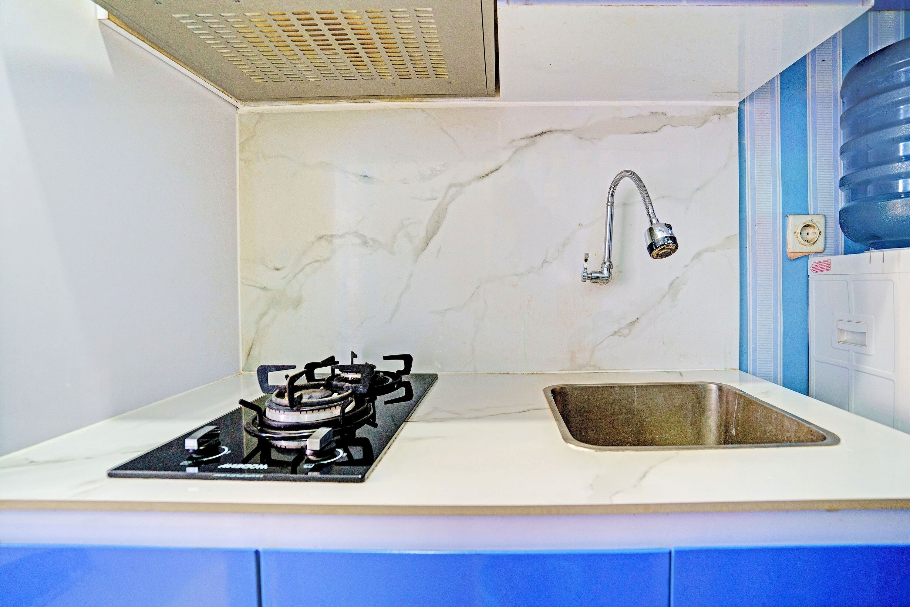 A kitchen with a gas stove, a sink, and a water dispenser.