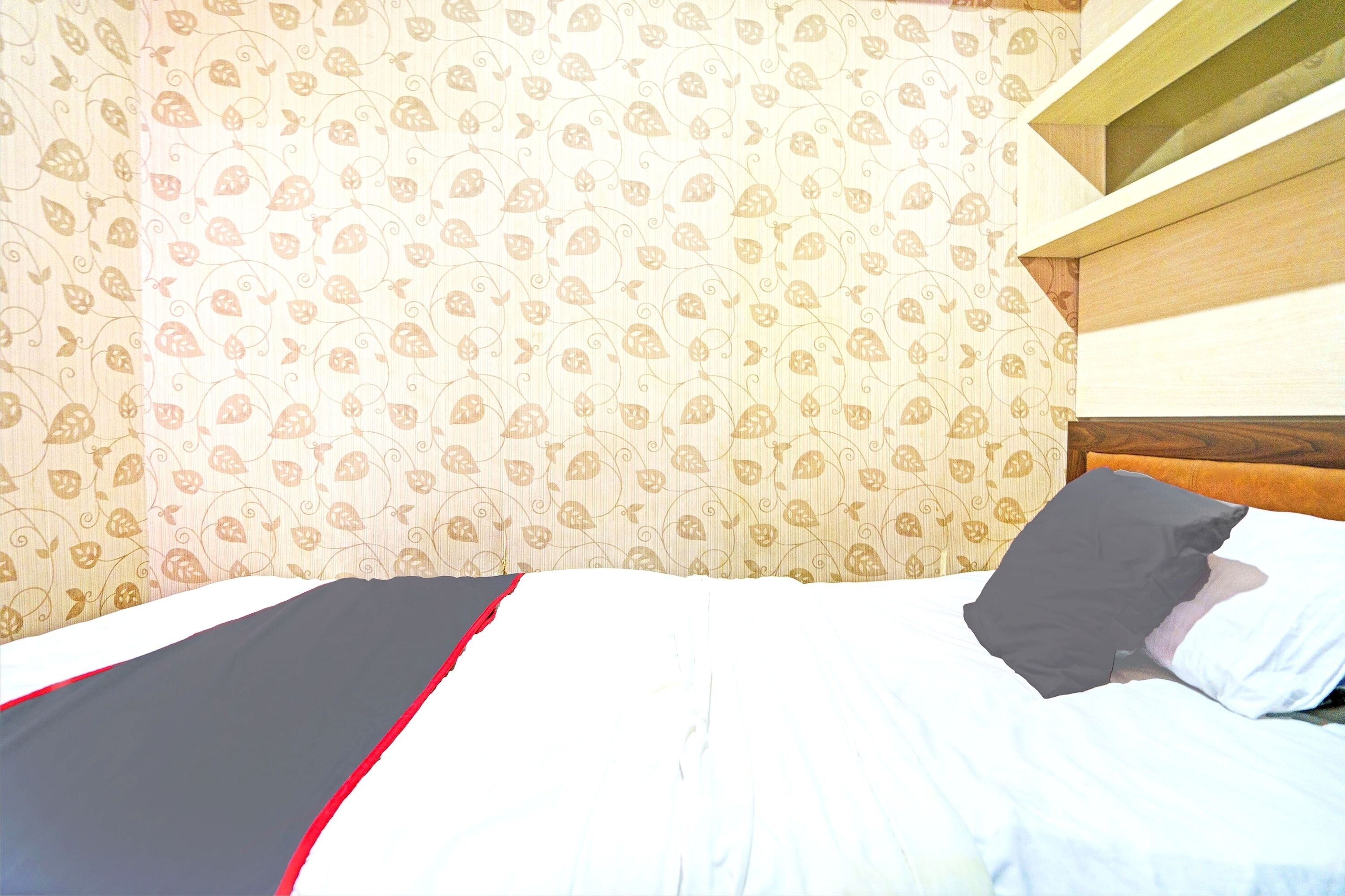 A bed with a white and black bedspread, a black pillow, and a wooden headboard.