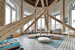 Spazioso loft con travi a vista in legno, ampie finestre e pavimento a motivi.