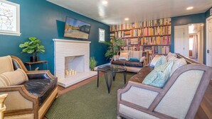 Un salon avec une cheminée, un canapé, une table basse et une bibliothèque remplie de livres.