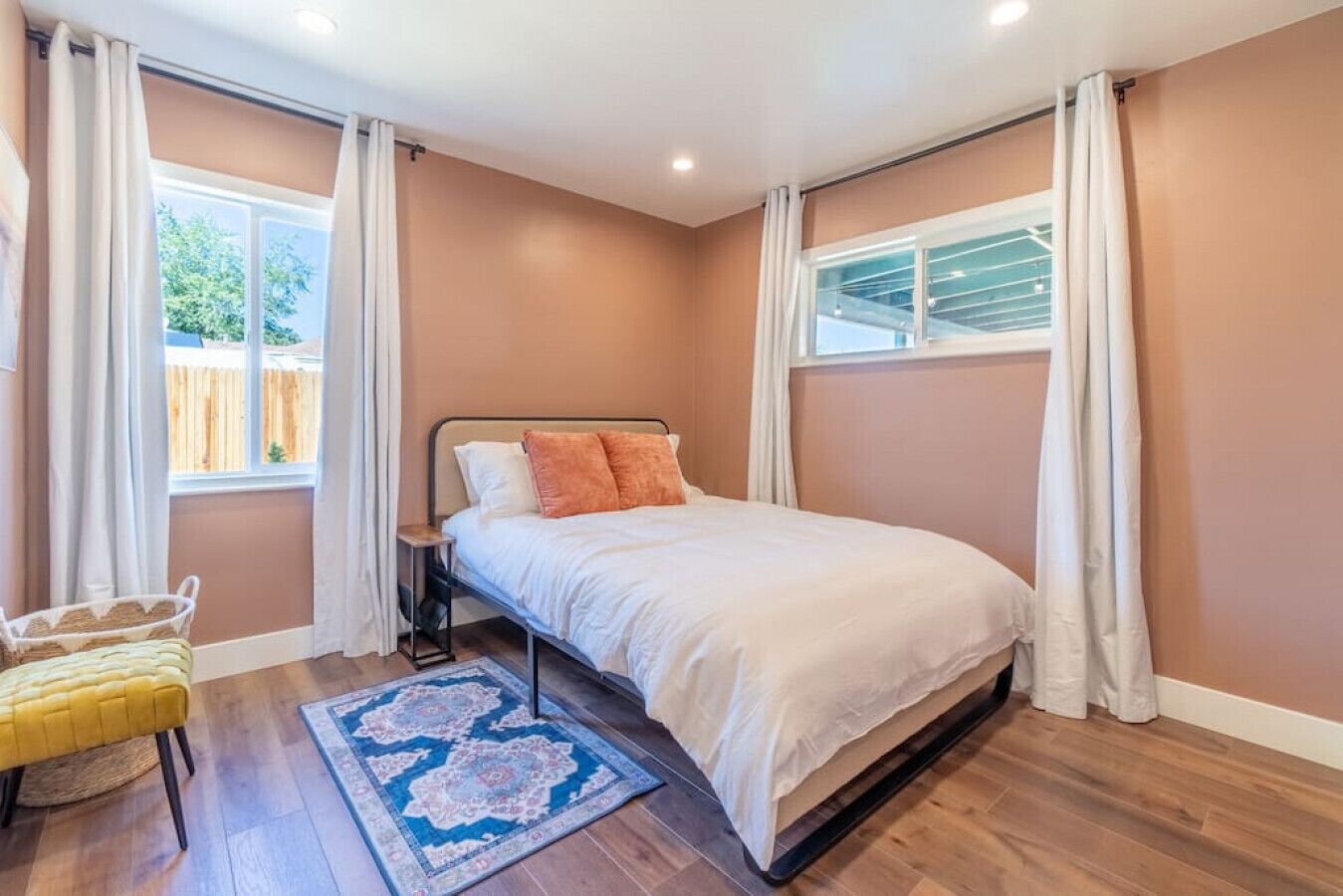 A bedroom with a bed, a nightstand, a chair, a window, and a door.