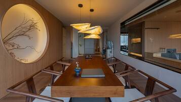 A modern dining area with a long wooden table, chairs, and a unique wall art piece.