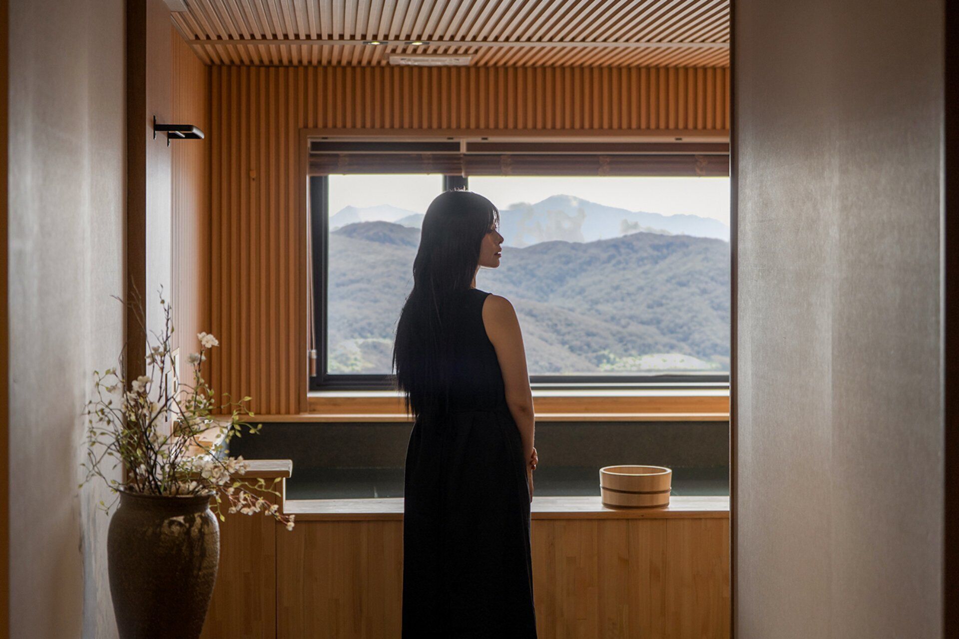 Una habitación con un ventanal grande, paneles de madera, una planta en maceta y un cuenco de madera en el alféizar.