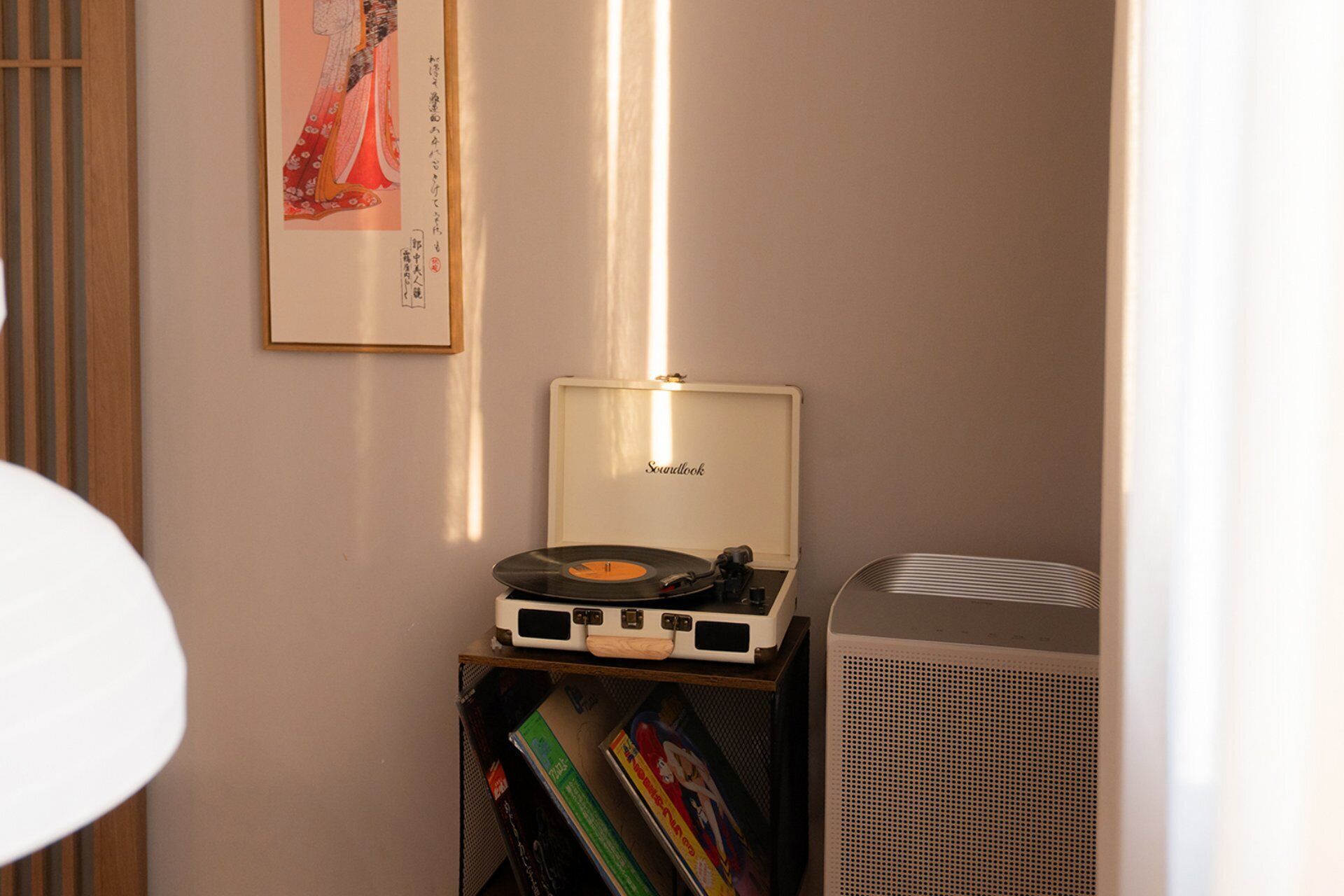 A room with a vintage Soundtrack turntable, a large air conditioning unit, and a framed picture on the wall.