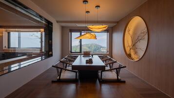 Un comedor moderno con una mesa larga, sillas, luces colgantes y un amplio ventanal con vistas.