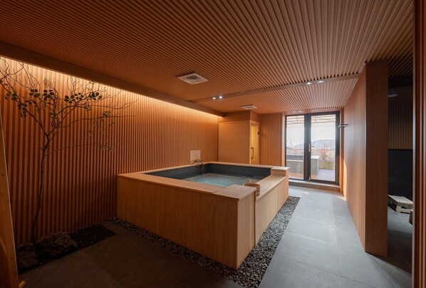 Un spa moderno con interior de madera, un jacuzzi y vistas a través de un ventanal.