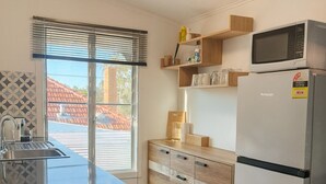 A modern kitchen with a built-in microwave, a refrigerator, and wooden cabinets. - Cosy and private self contained retreat in a great location, pet friendly (Graceville)