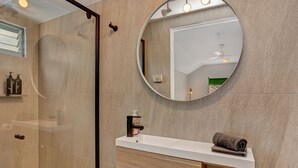 A modern bathroom with a glass shower enclosure, a round mirror, a white countertop vanity, and a towel on the counter. - Cosy and private self contained retreat in a great location, pet friendly (Graceville)