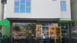 A restaurant with outdoor seating, a green awning, and a menu board outside. - Contento Retreat (Hulhumalé)