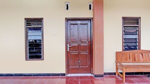 A wooden door with a number plate, a window with shutters, and a bench. - SPOT ON 93007 Guest House Lestari (Prambanan)