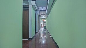 Um corredor comprido e estreito, com paredes verdes e piso de azulejos.