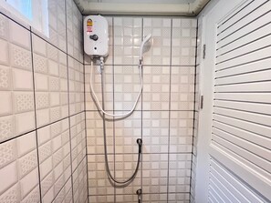 Ein kleiner Duschbereich mit Fliesen, Bedienfeld und Handbrause.