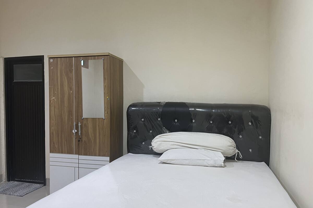 A bedroom with a bed, a wardrobe, and a door.