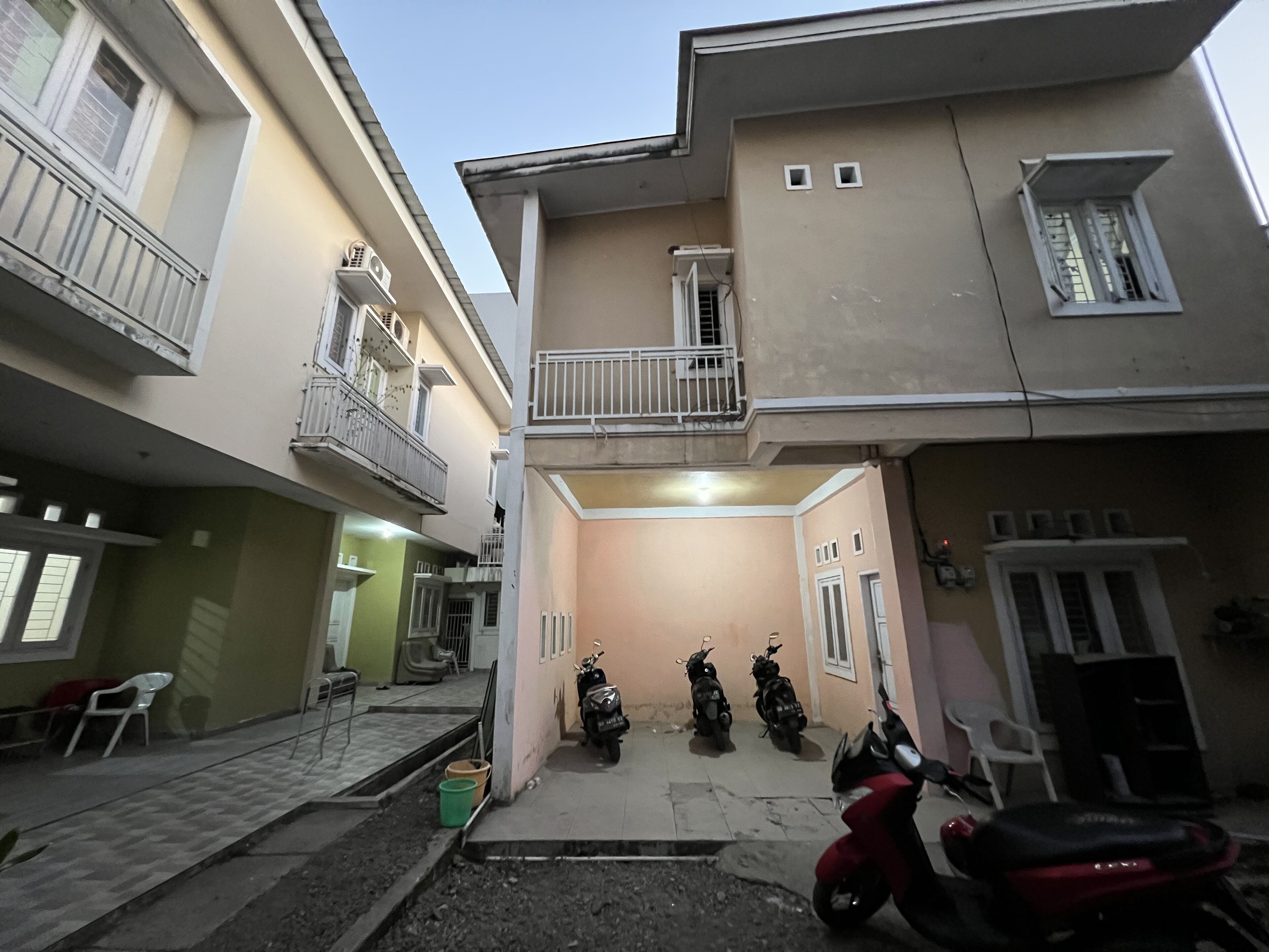Un edificio residencial de varios pisos con balcones, una entrada con reja y motocicletas estacionadas.