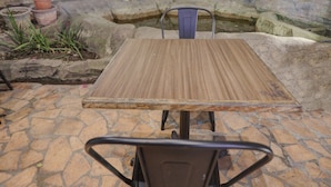 Un patio de piedra con una mesa de madera y sillas de metal.