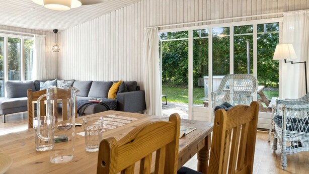 A modern interior with a wooden dining table, a sofa, and wicker chairs. - "Arwin" - 200m from the sea by Interhome (Hadsund)
