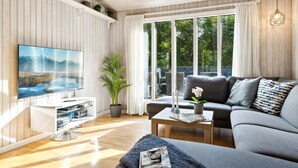 A modern living room with a large TV, a grey sofa, a coffee table, and a potted plant. - "Arwin" - 200m from the sea by Interhome (Hadsund)
