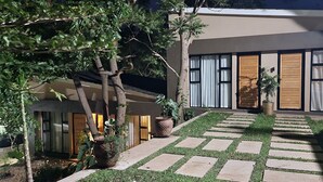 A modern house with a paved garden area, large windows, and potted plants. - Instahomes by Tru - Garden Suites (Blantyre)