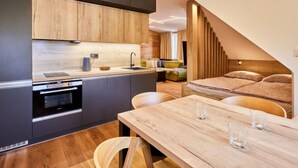 Una cocina moderna con armarios de madera, horno integrado y comedor con mesa y sillas de madera.