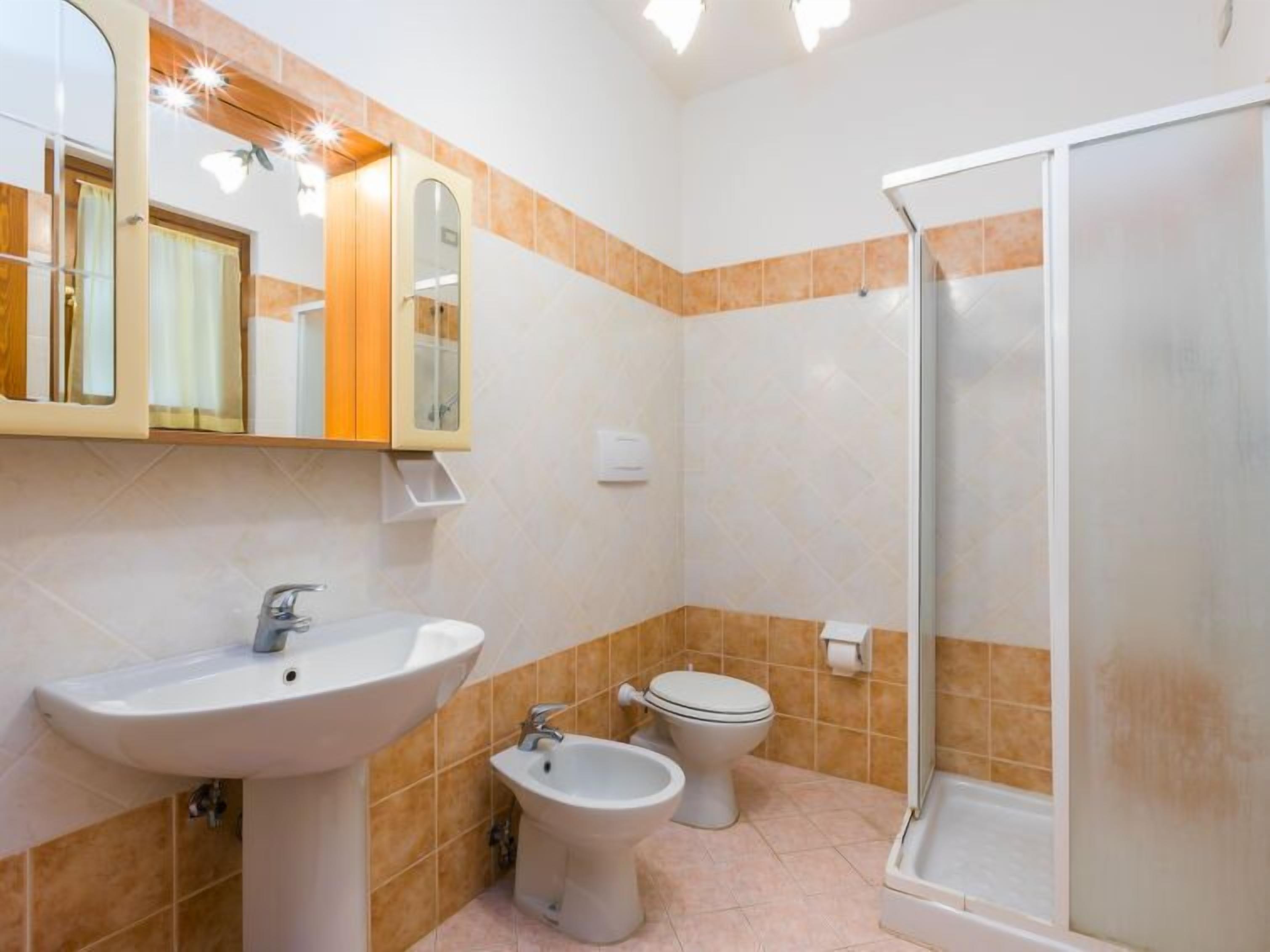 A bathroom with a sink, bidet, toilet, and a shower stall.