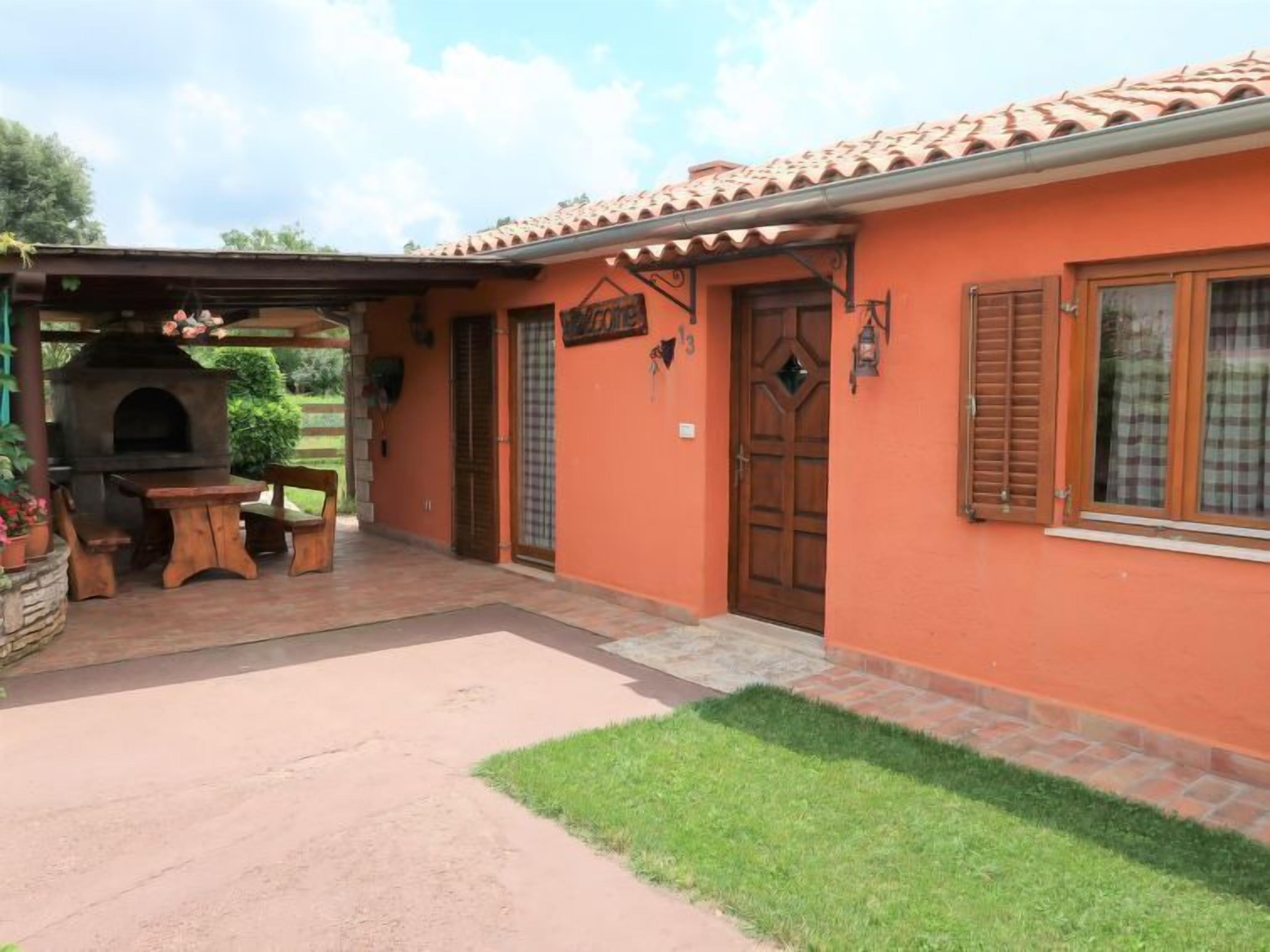 A house with a patio, a barbecue area, and a small garden.